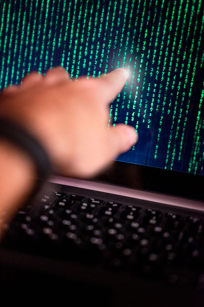 Claves para blindar la infraestructura tecnológica de tu empresa en 2026 A person points at a glowing code on a computer screen, symbolizing technology interaction.